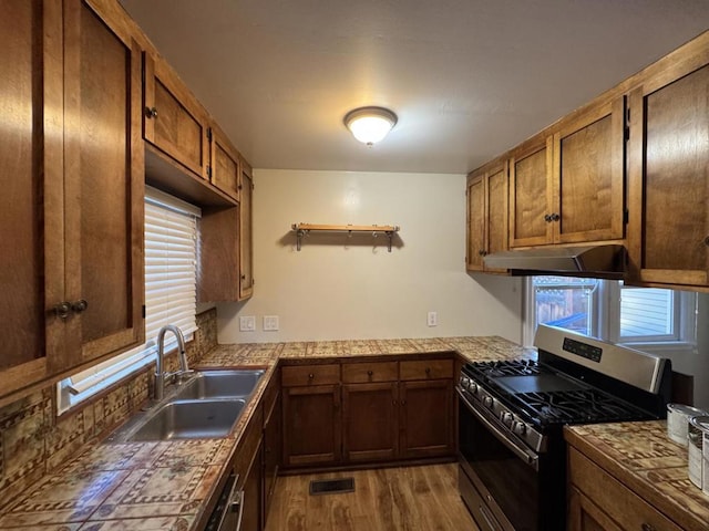 kitchen featuring sink, a wealth of natural light, stainless steel gas range, and light hardwood / wood-style flooring