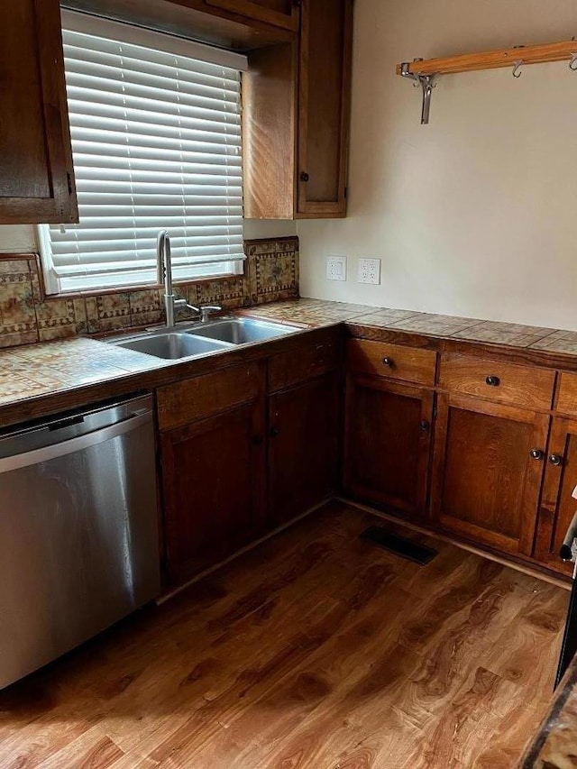 kitchen featuring sink, dark hardwood / wood-style floors, tasteful backsplash, a healthy amount of sunlight, and stainless steel dishwasher