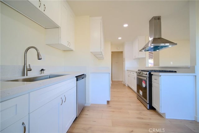 kitchen featuring sink, stainless steel appliances, island range hood, light hardwood / wood-style floors, and white cabinets