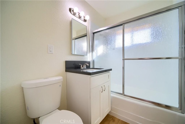 full bathroom featuring vanity, hardwood / wood-style floors, toilet, and combined bath / shower with glass door