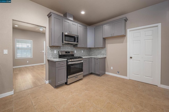 kitchen with ceiling fan, gray cabinets, stainless steel appliances, and tasteful backsplash