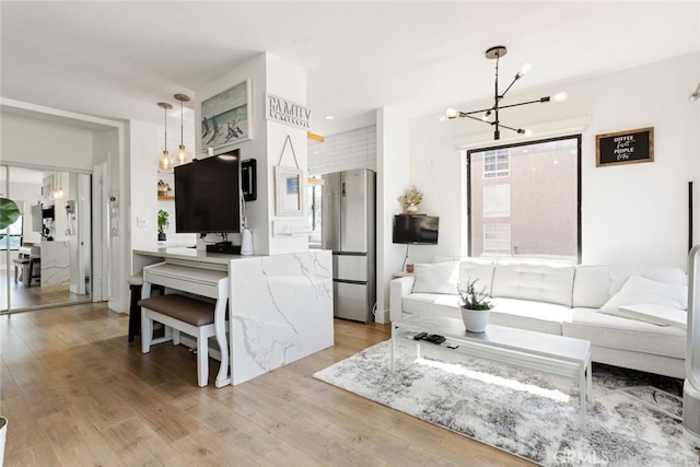 living room with light wood-type flooring and an inviting chandelier