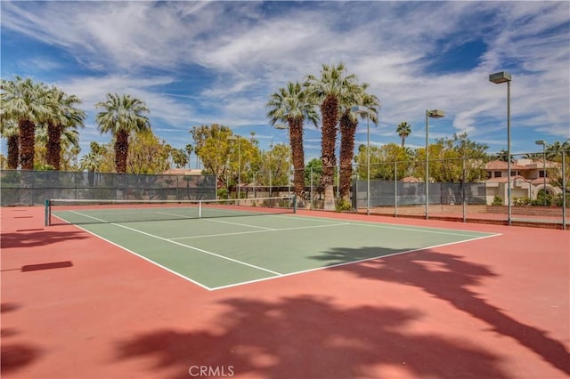 view of tennis court with community basketball court and fence