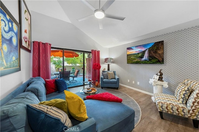 living room with lofted ceiling, a ceiling fan, wood finished floors, baseboards, and wallpapered walls