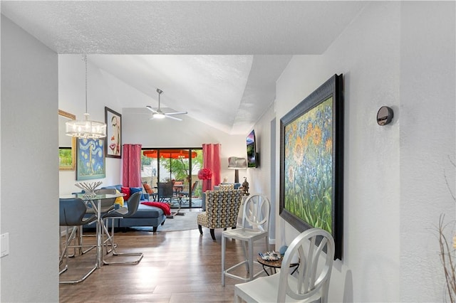 interior space with lofted ceiling, a textured ceiling, ceiling fan with notable chandelier, and wood finished floors