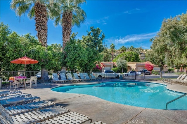 pool with a patio area and fence