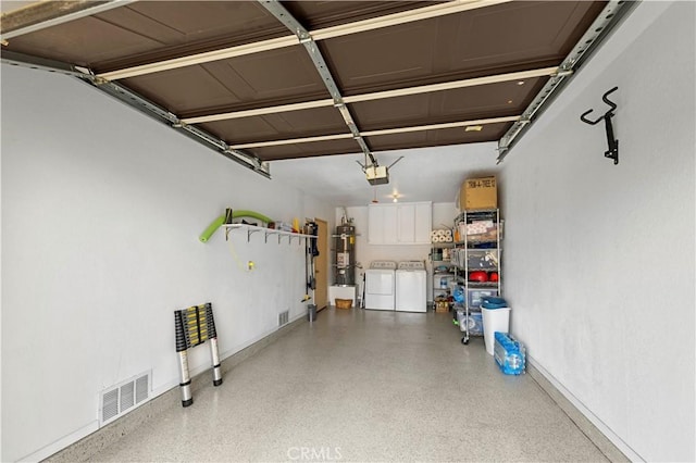 garage with visible vents, baseboards, a garage door opener, secured water heater, and washing machine and dryer