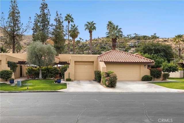 view of front of property with concrete driveway, a tile roof, an attached garage, and stucco siding