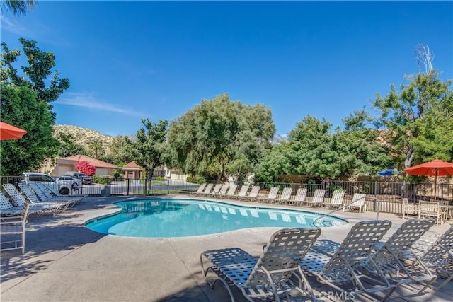 community pool with a patio, fence, and a mountain view