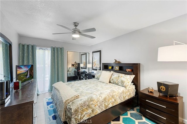 bedroom featuring a textured ceiling, a closet, wood finished floors, and a ceiling fan