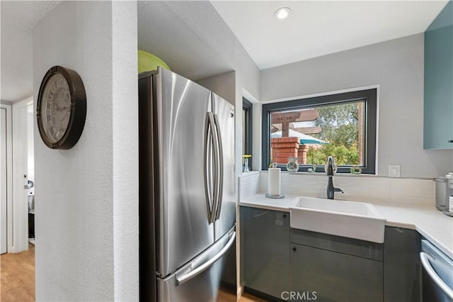 kitchen with light countertops, appliances with stainless steel finishes, a sink, and light wood-style floors