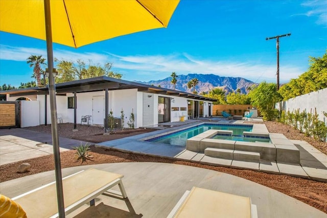 view of pool with an in ground hot tub, a patio area, and a mountain view