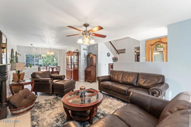 tiled living room with ceiling fan with notable chandelier