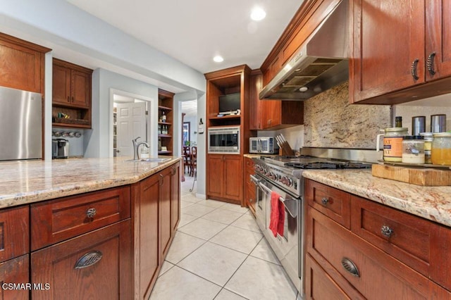 kitchen with light stone countertops, sink, stainless steel appliances, and extractor fan