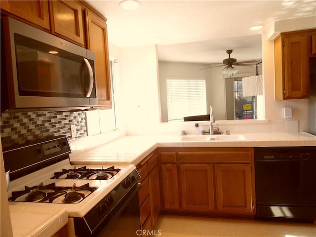 kitchen featuring sink, black dishwasher, tasteful backsplash, gas range oven, and tile countertops