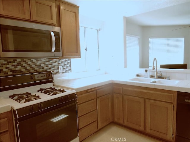 kitchen with gas stove, sink, tile counters, and decorative backsplash