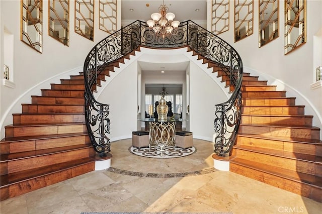 foyer with a notable chandelier, a towering ceiling, baseboards, and stairs