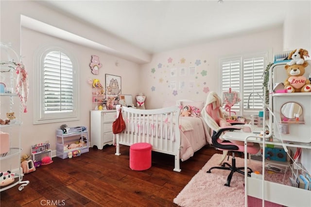 bedroom featuring dark hardwood / wood-style floors and a nursery area