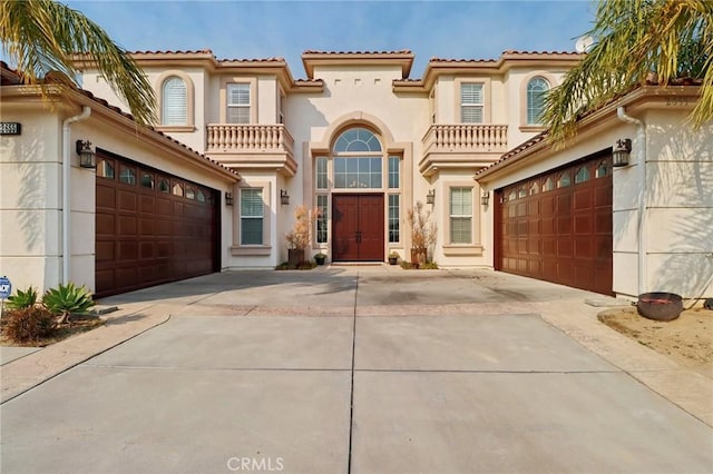 mediterranean / spanish home featuring a garage, driveway, a tiled roof, and stucco siding