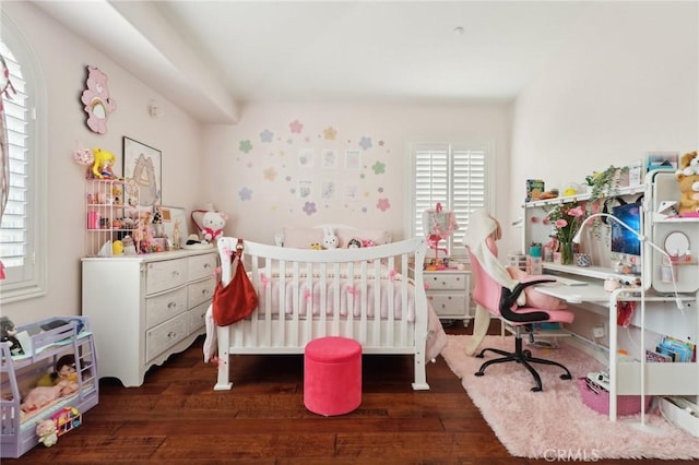 bedroom with a crib and dark hardwood / wood-style floors