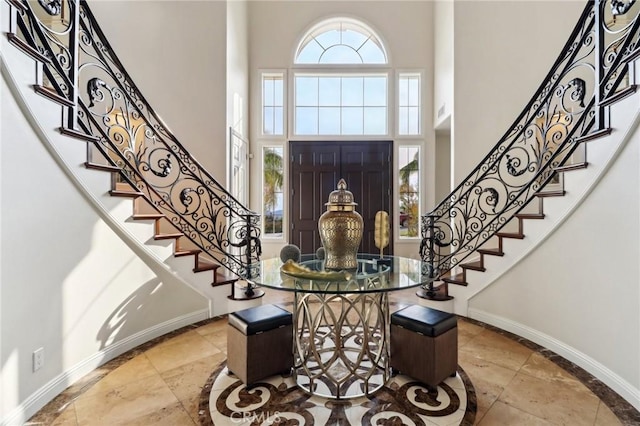 foyer entrance with a towering ceiling, baseboards, and stairs