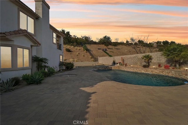 pool at dusk featuring a fenced backyard, a fenced in pool, and a patio