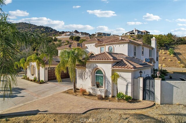 mediterranean / spanish-style home with fence, a tile roof, driveway, a gate, and stucco siding