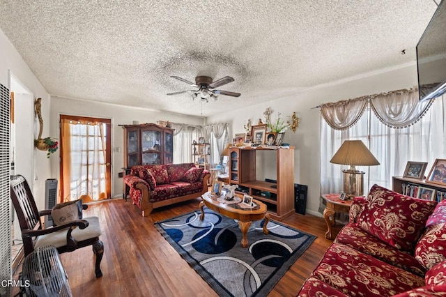 living room with ceiling fan, plenty of natural light, dark hardwood / wood-style flooring, and a textured ceiling