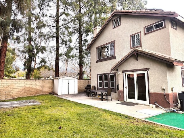 back of house featuring a yard, a storage shed, and a patio