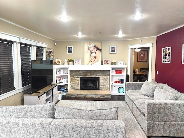 living room with wood-type flooring, crown molding, and a stone fireplace