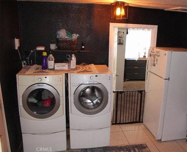 laundry area with light tile patterned floors and washing machine and dryer