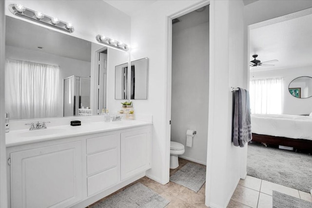 bathroom featuring toilet, ceiling fan, tile patterned floors, walk in shower, and vanity