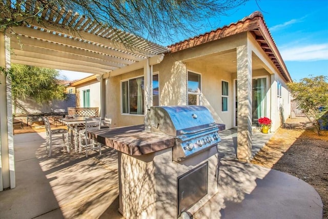 view of patio / terrace with exterior kitchen, a grill, and a pergola