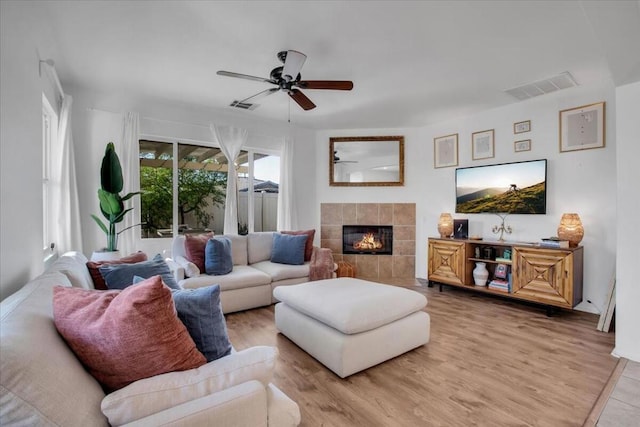 living room with ceiling fan, a fireplace, and light hardwood / wood-style flooring