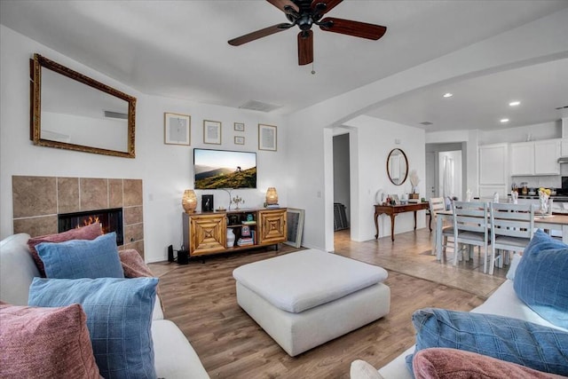 living room featuring light hardwood / wood-style floors, ceiling fan, and a fireplace