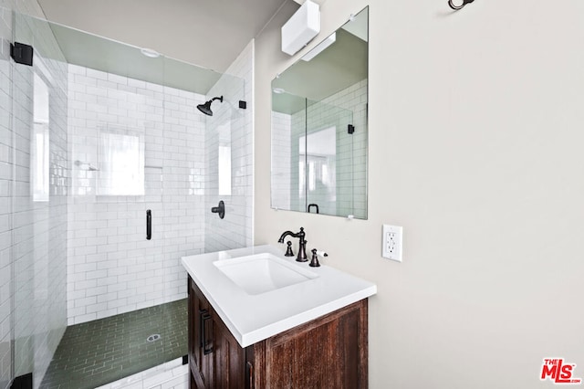 bathroom featuring a shower with door and vanity