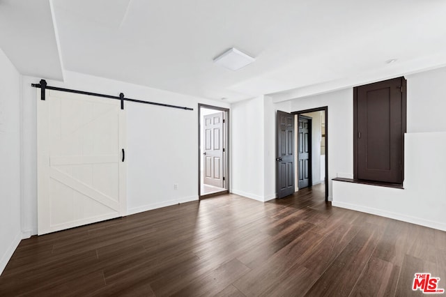 empty room with dark wood-type flooring and a barn door