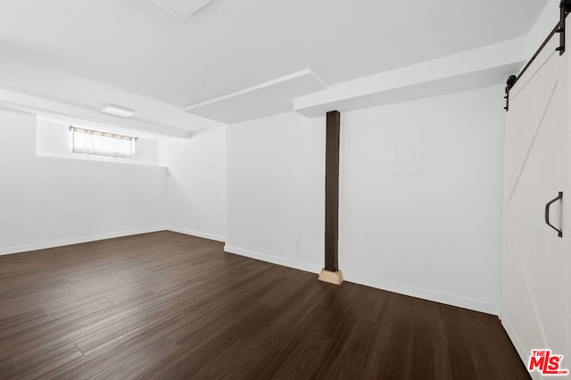 basement featuring a barn door and dark wood-type flooring