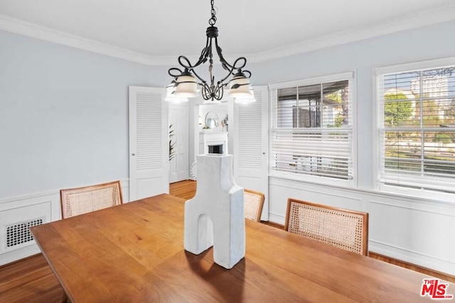 dining area with crown molding, an inviting chandelier, and hardwood / wood-style flooring