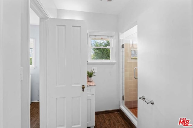 bathroom with wood-type flooring and a shower with door