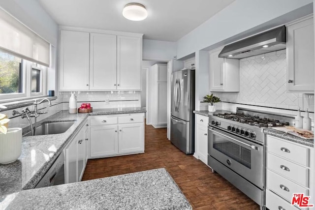 kitchen featuring sink, appliances with stainless steel finishes, wall chimney range hood, and white cabinetry