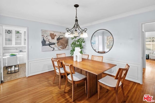 dining space featuring an inviting chandelier, ornamental molding, and light hardwood / wood-style floors