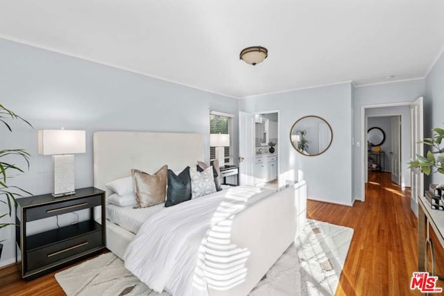 bedroom featuring ensuite bath and hardwood / wood-style flooring