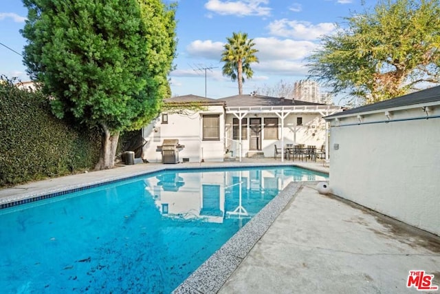 view of pool with a patio area and a grill