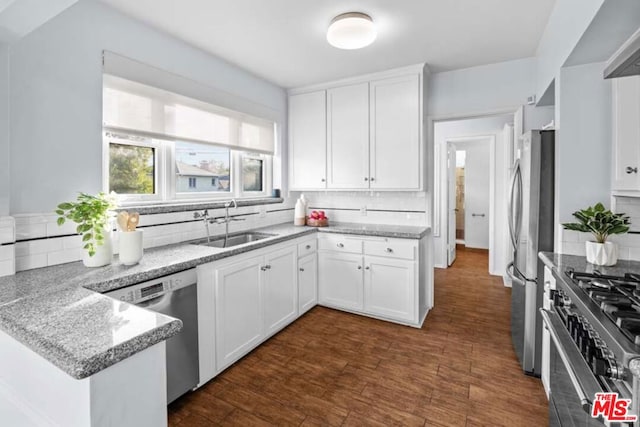 kitchen with white cabinets, backsplash, light stone counters, and stainless steel appliances