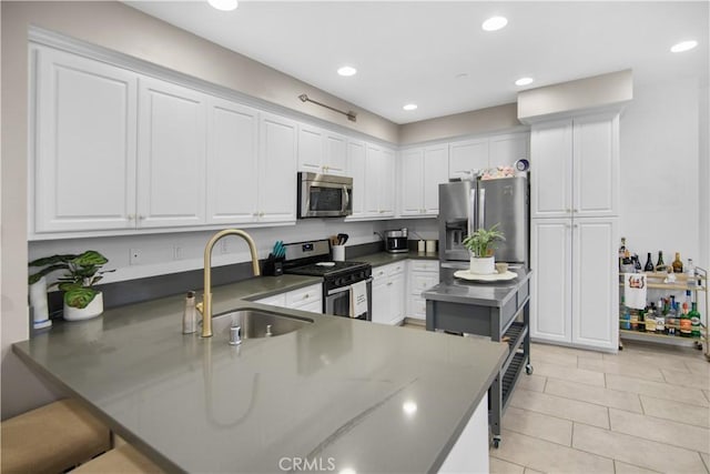 kitchen featuring white cabinets, kitchen peninsula, appliances with stainless steel finishes, and sink