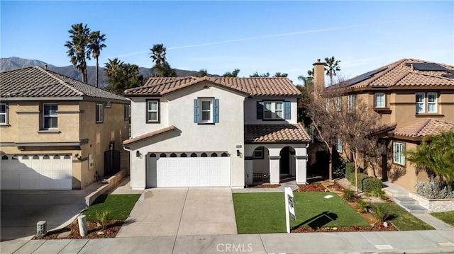 mediterranean / spanish-style home with a garage, a mountain view, and a front lawn