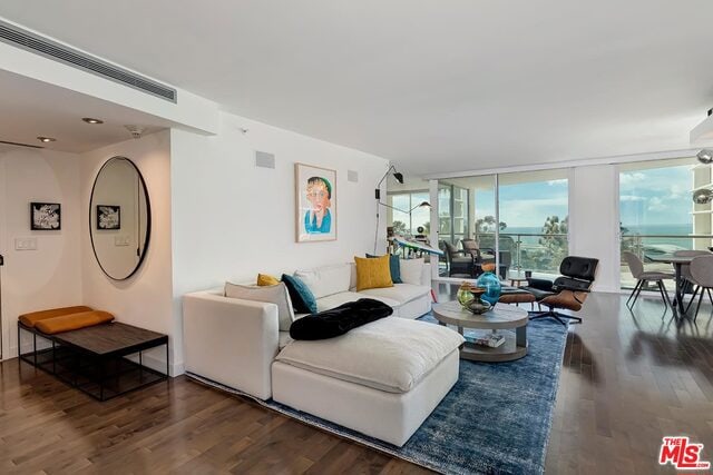 living room featuring dark wood-type flooring and floor to ceiling windows