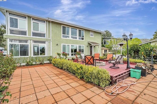 rear view of property featuring a patio area, an outdoor fire pit, and a wooden deck