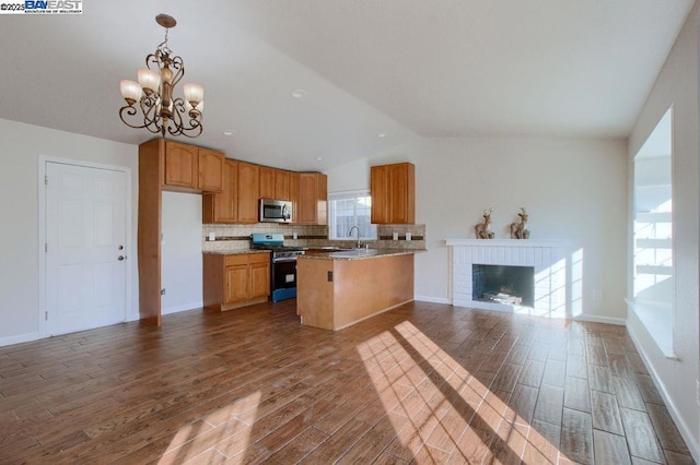 kitchen featuring appliances with stainless steel finishes, a fireplace, hanging light fixtures, vaulted ceiling, and a chandelier